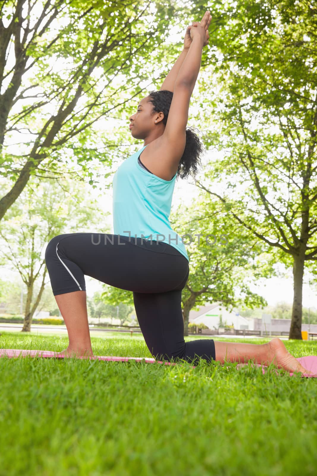 Young woman doing yoga on mat in the park