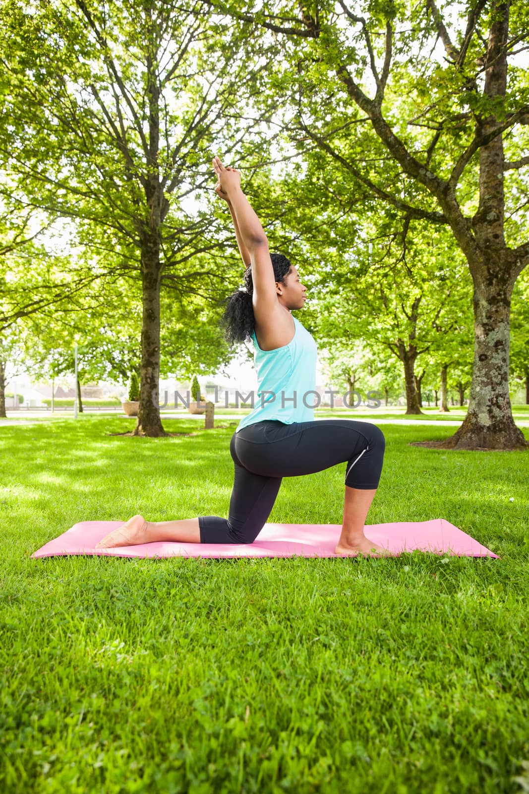 Young woman doing yoga on mat in the park