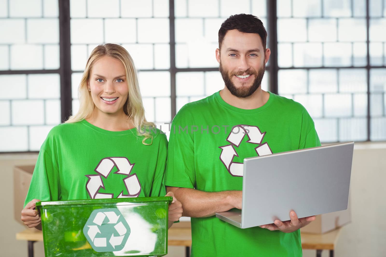 Portrait of smiling volunteers in recycling symbol tshirts in creative office