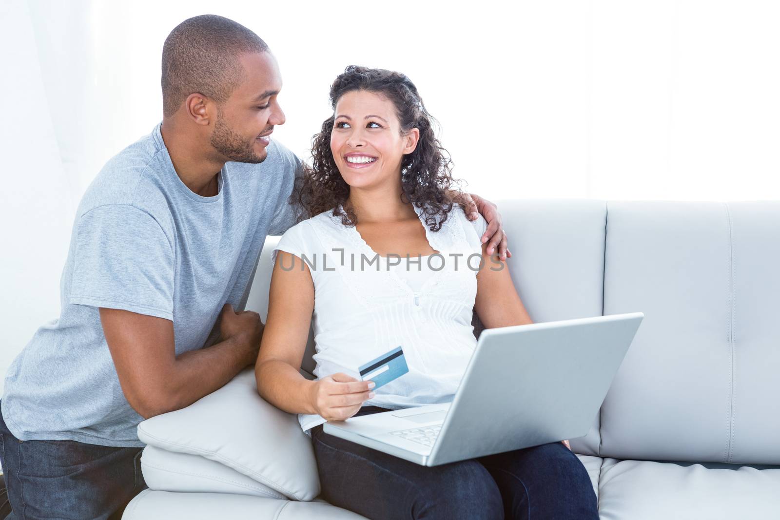 Happy couple shopping online sitting on sofa at home