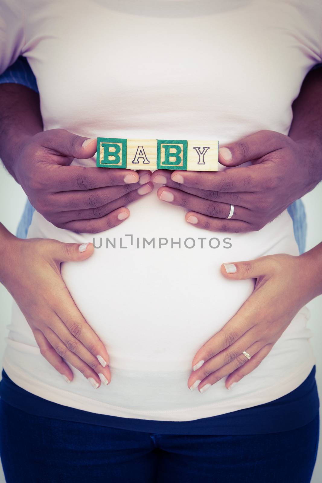 Midsection of pregnant woman with husband holding baby text 