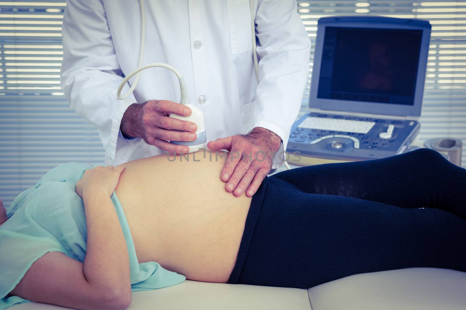 Male doctor performing ultrasound on woman in clinic