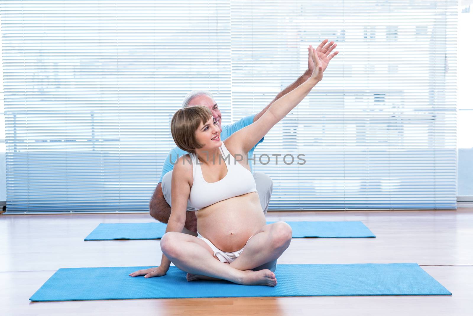 Instructor teaching yoga to pregnant woman in class