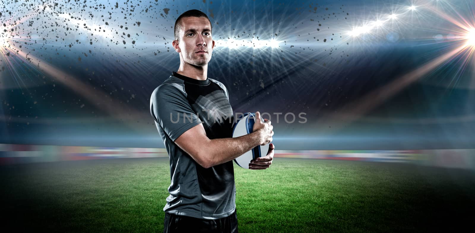 Confident rugby player in holding ball against rugby stadium