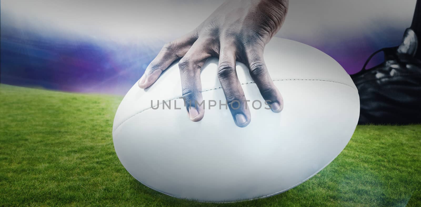 Cropped image of sportsman holding rugby ball against rugby stadium