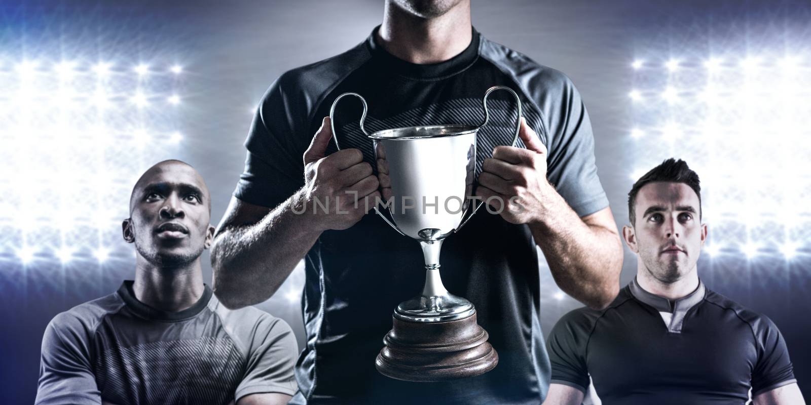 Victorious rugby player holding trophy against spotlight