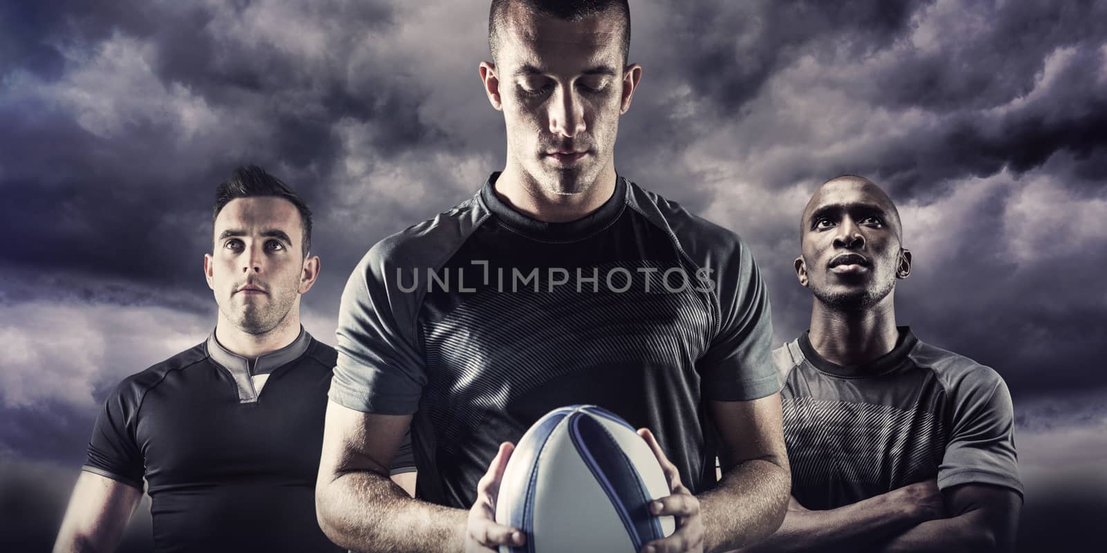 Thoughtful rugby player holding ball against blue sky