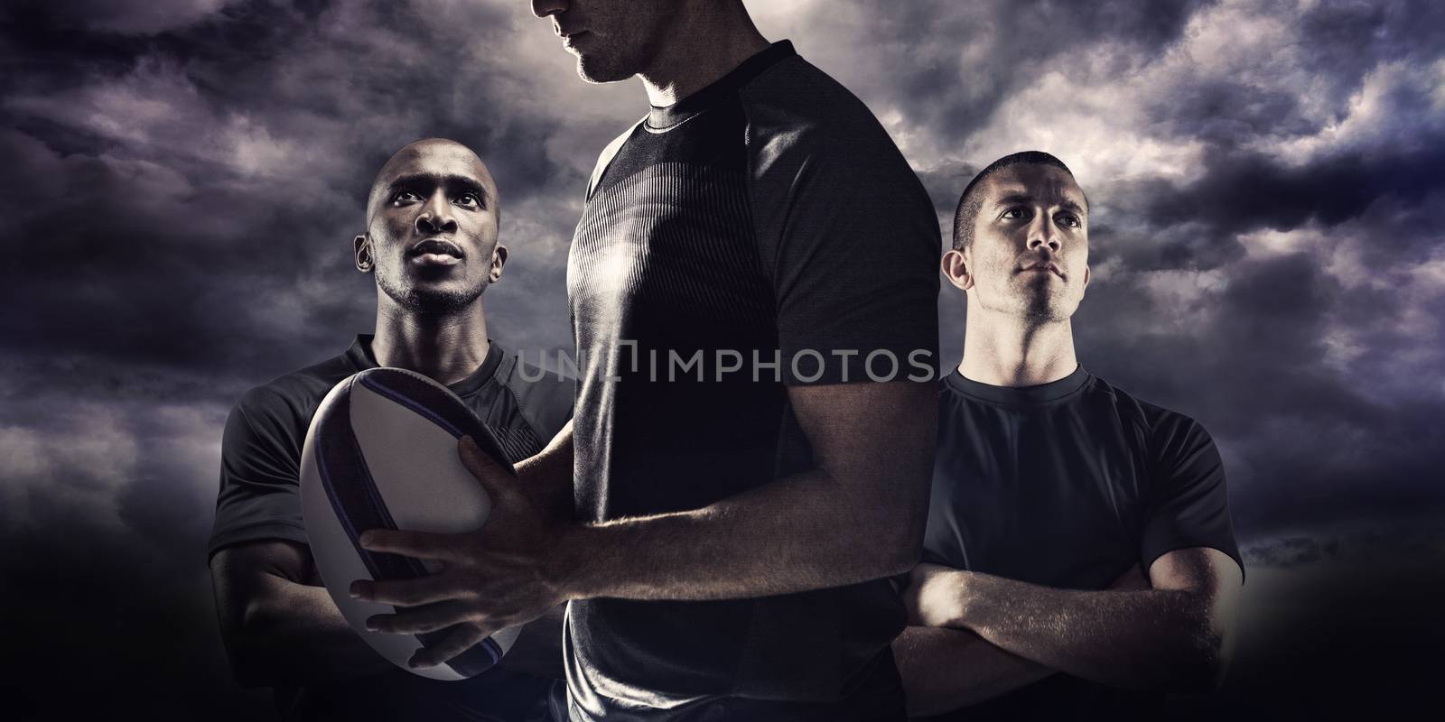 Calm rugby player thinking while holding ball against blue sky