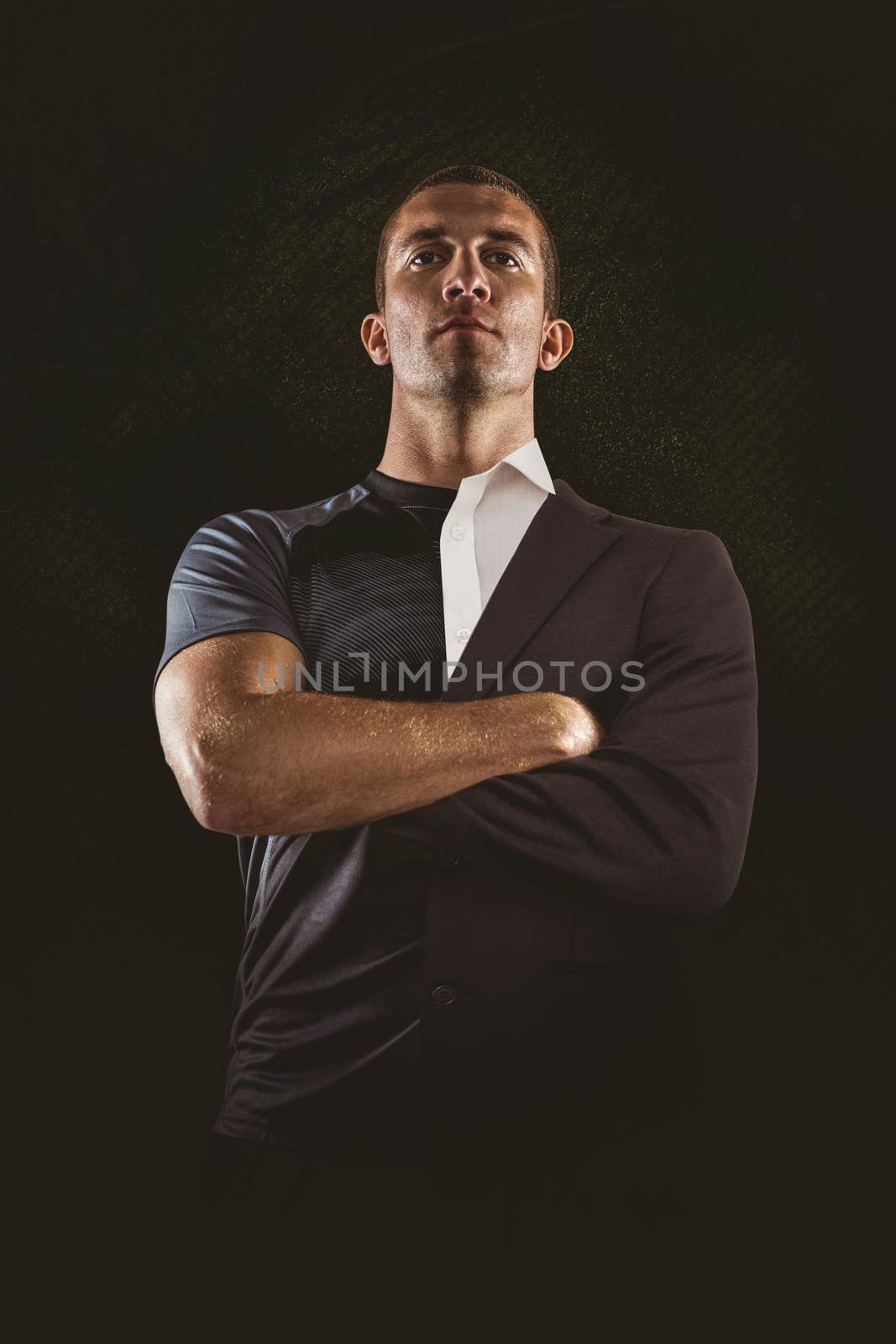 Confident rugby player with arms crossed against half a suit