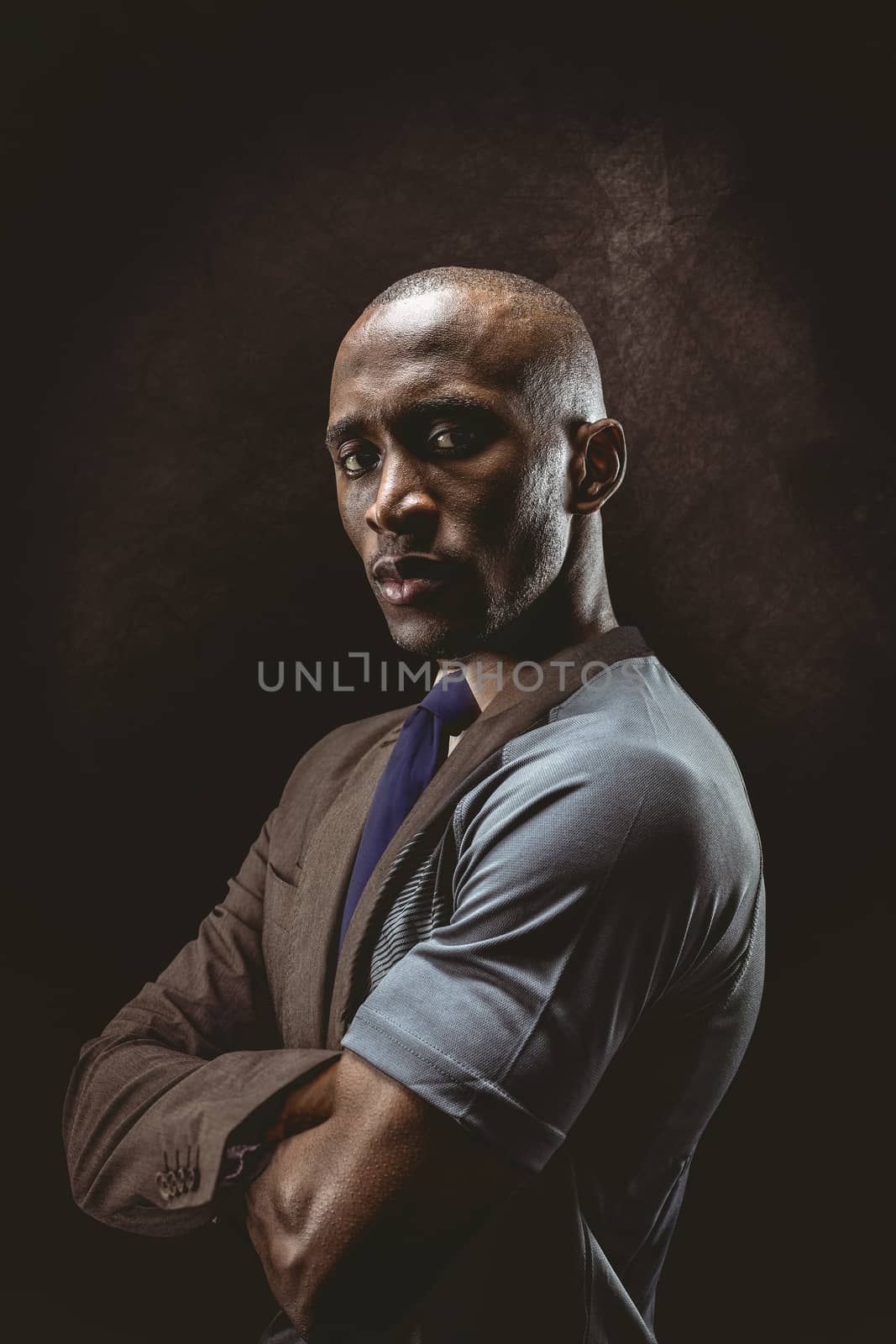 Portrait of confident athlete with arms crossed against half a suit