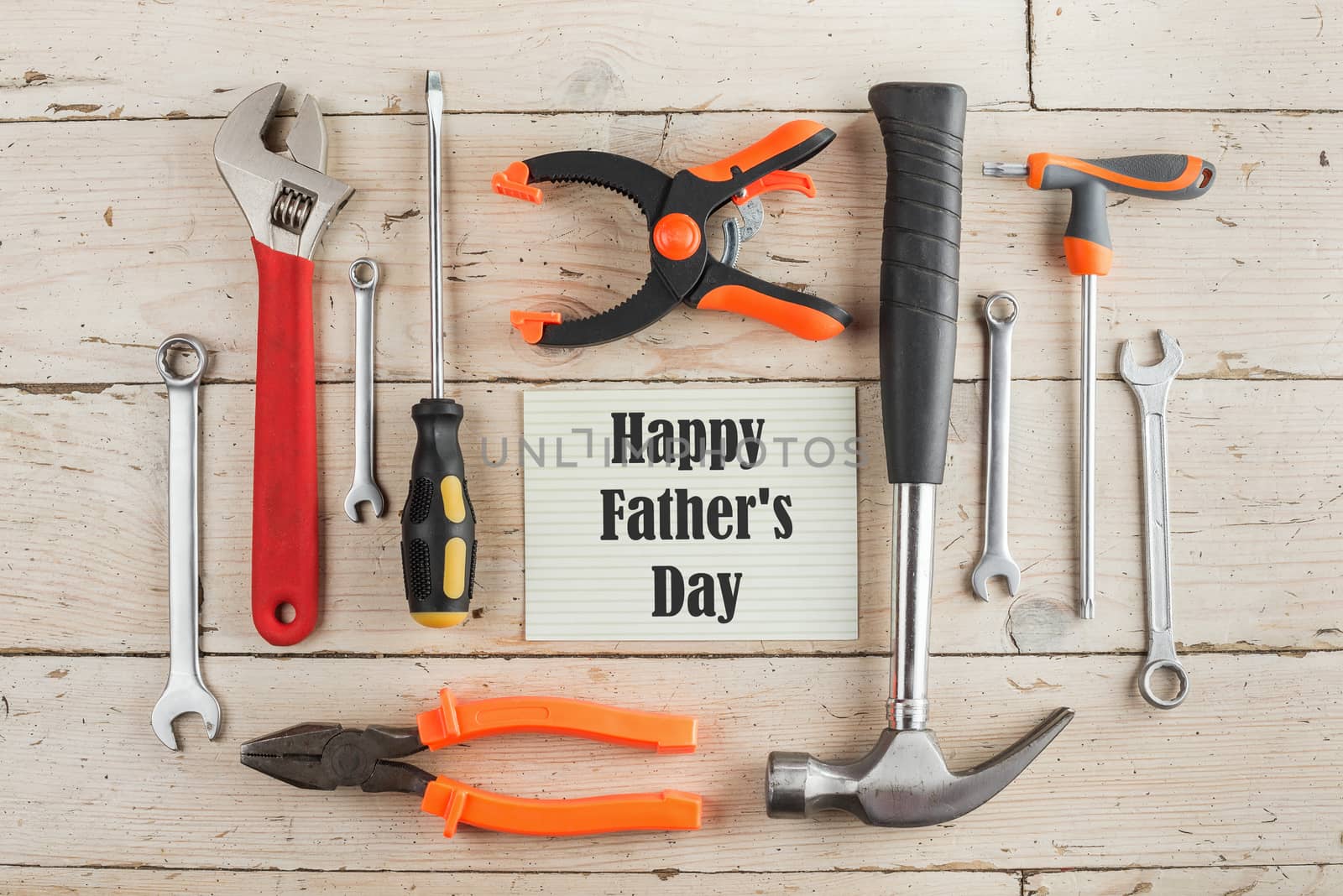 Greeting Card to Happy Father's Day, concept, set of different tools: a hammer, Hand saw, pliers, wrench, screwdriver, various spanners, clamp on a wooden background and text , closeup, top view