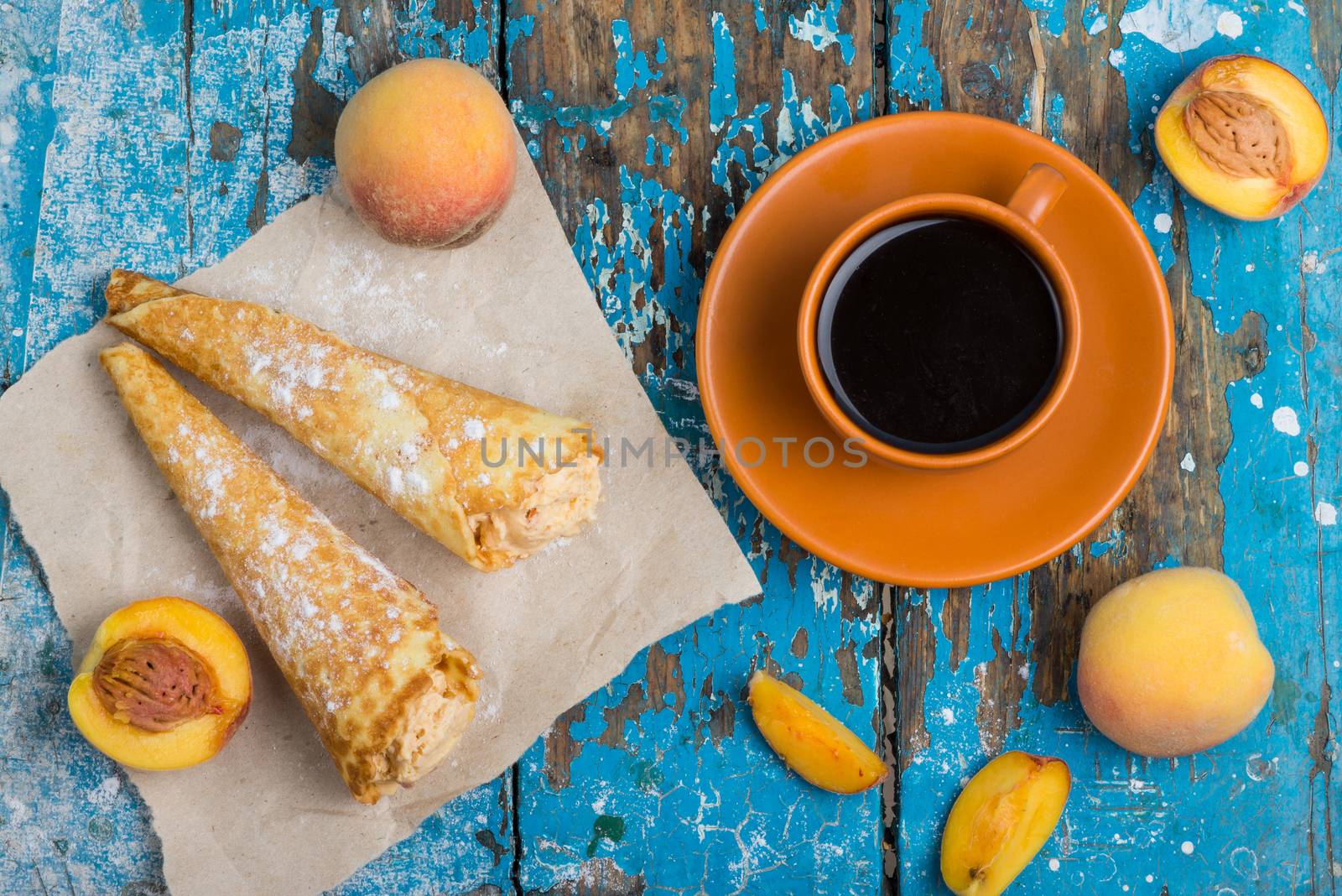 Good morning, Have a nice day. A cup of coffee, delicious waffles with peach ice cream decorated with icing sugar and fresh peaches on old blue vintage wooden background, top view
