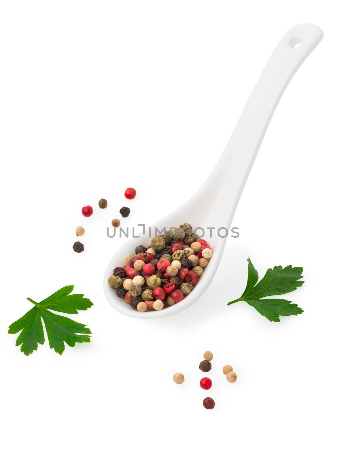 mix of different peppers in a white ceramic spoon and parsley leaves, mixture of hot pepper, red pepper, black pepper, white pepper, green pepper on a white  background