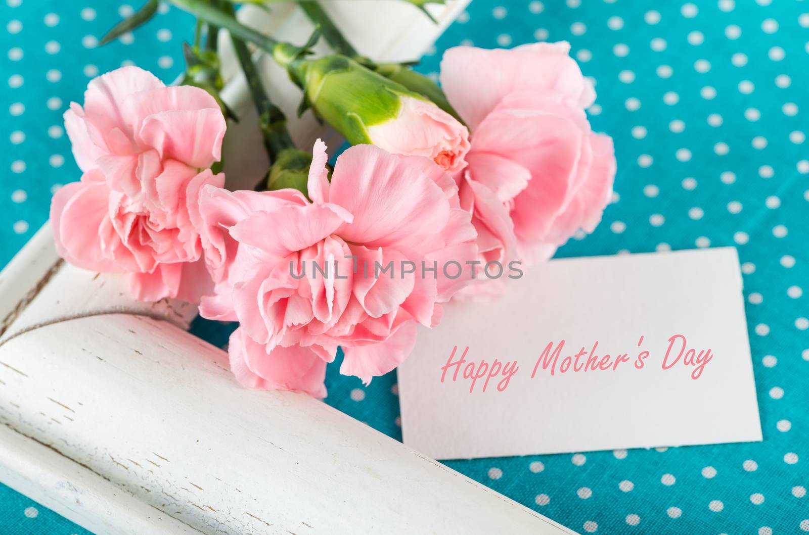 Greeting card with the inscription Happy Mothers Day with pink carnations on a bright blue background with white polka dots