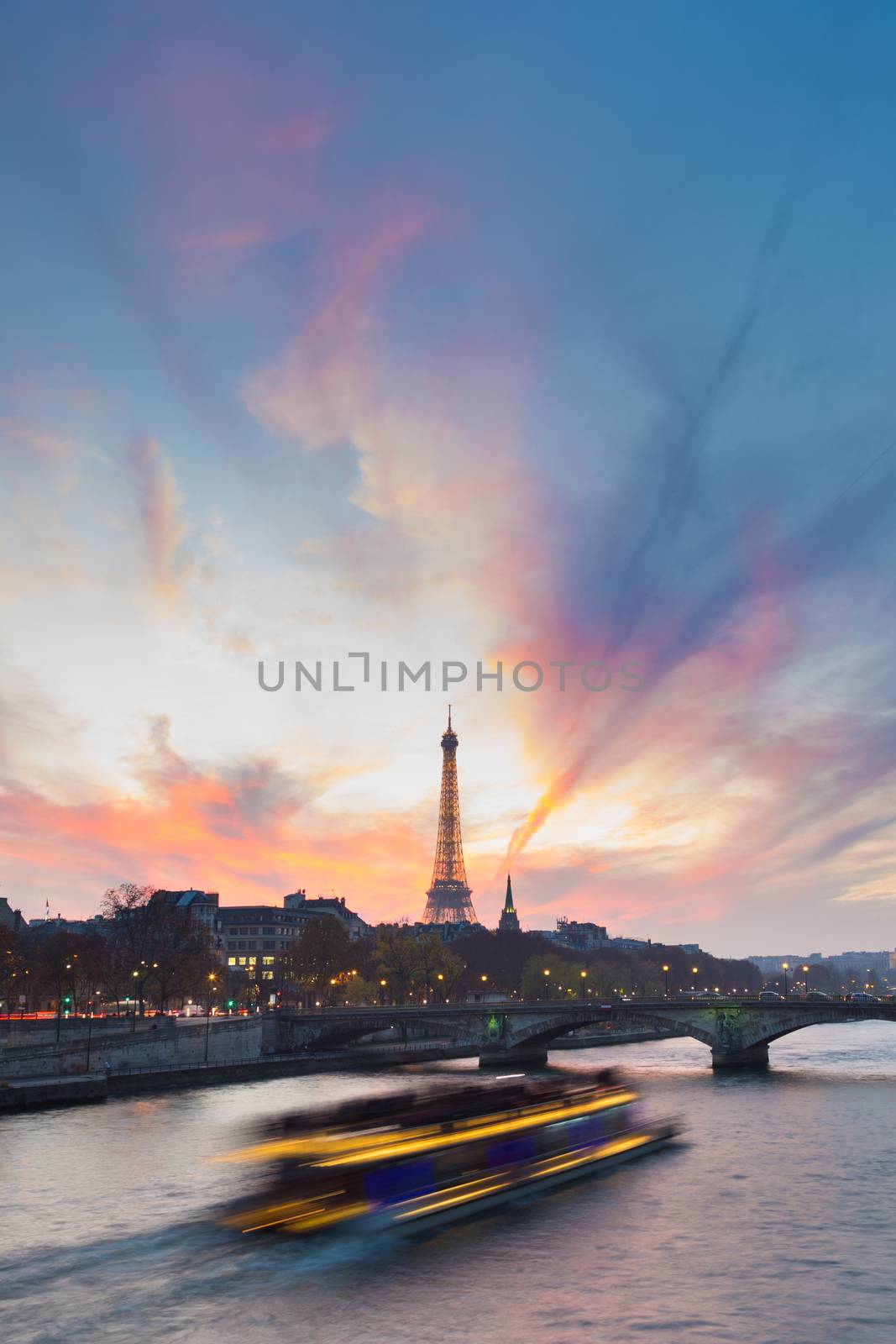 Beautiful colorful sunset over Eiffel Tower and Seine river. Paris, France. Illuminated tourist boat crousing on the river, enjoying the romantic view. Vertical composition. Copy space.