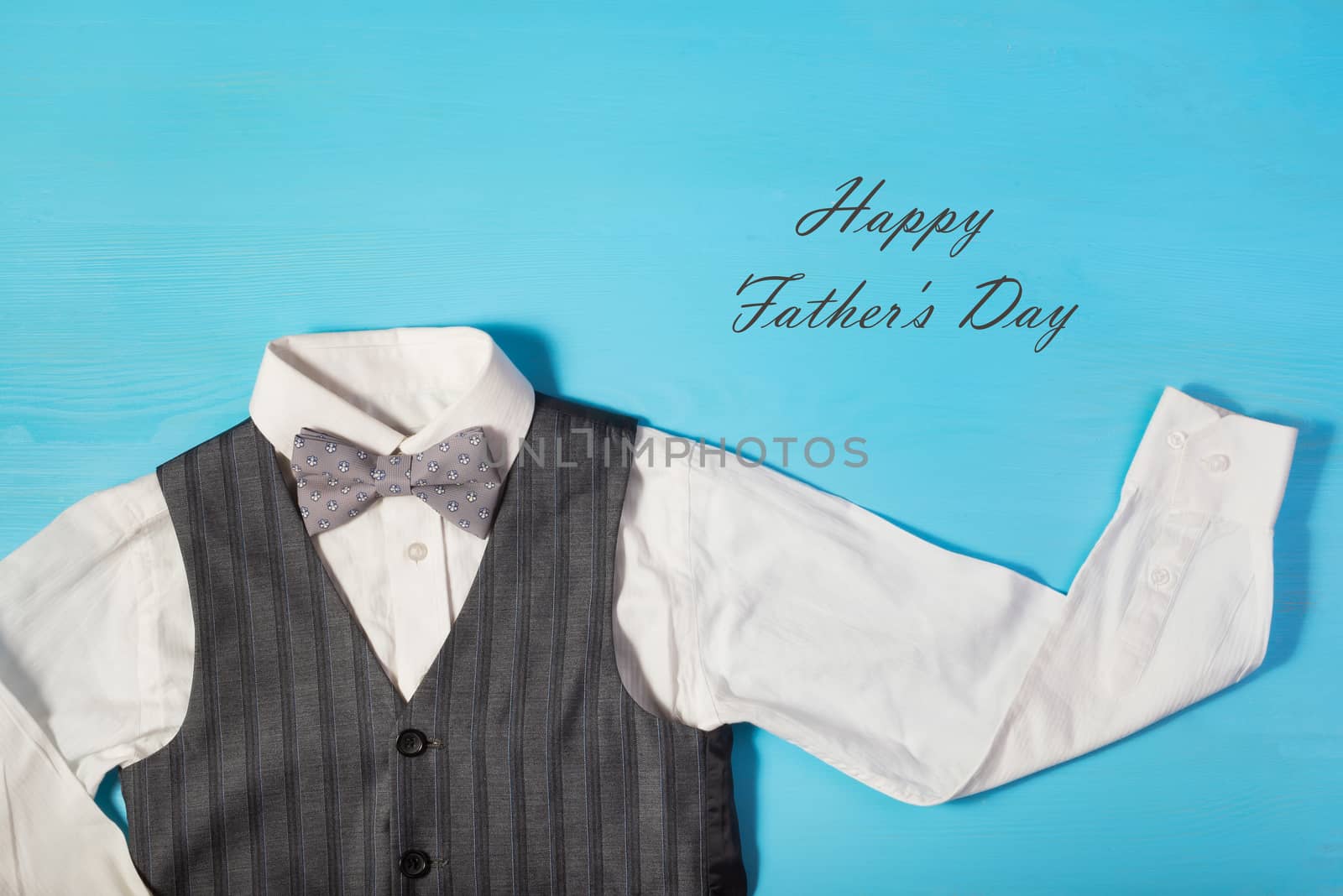 Greeting card for Dad's Day, white shirt, gray vest and a bow tie on a bright blue background, and text happy Father's Day