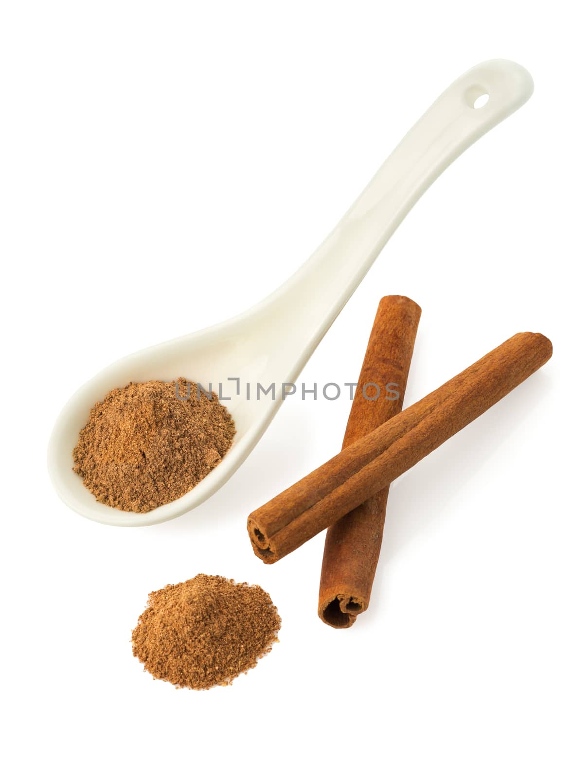Ground cinnamon in a white ceramic spoon, two cinnamon sticks isolated on white background