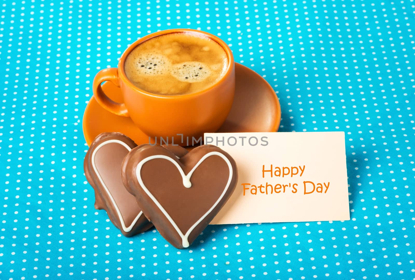 ceramic cup with coffee  espresso, tablet with text Happy Father's Day and two chocolate marzipan candy hearts on a bright blue background, love concept