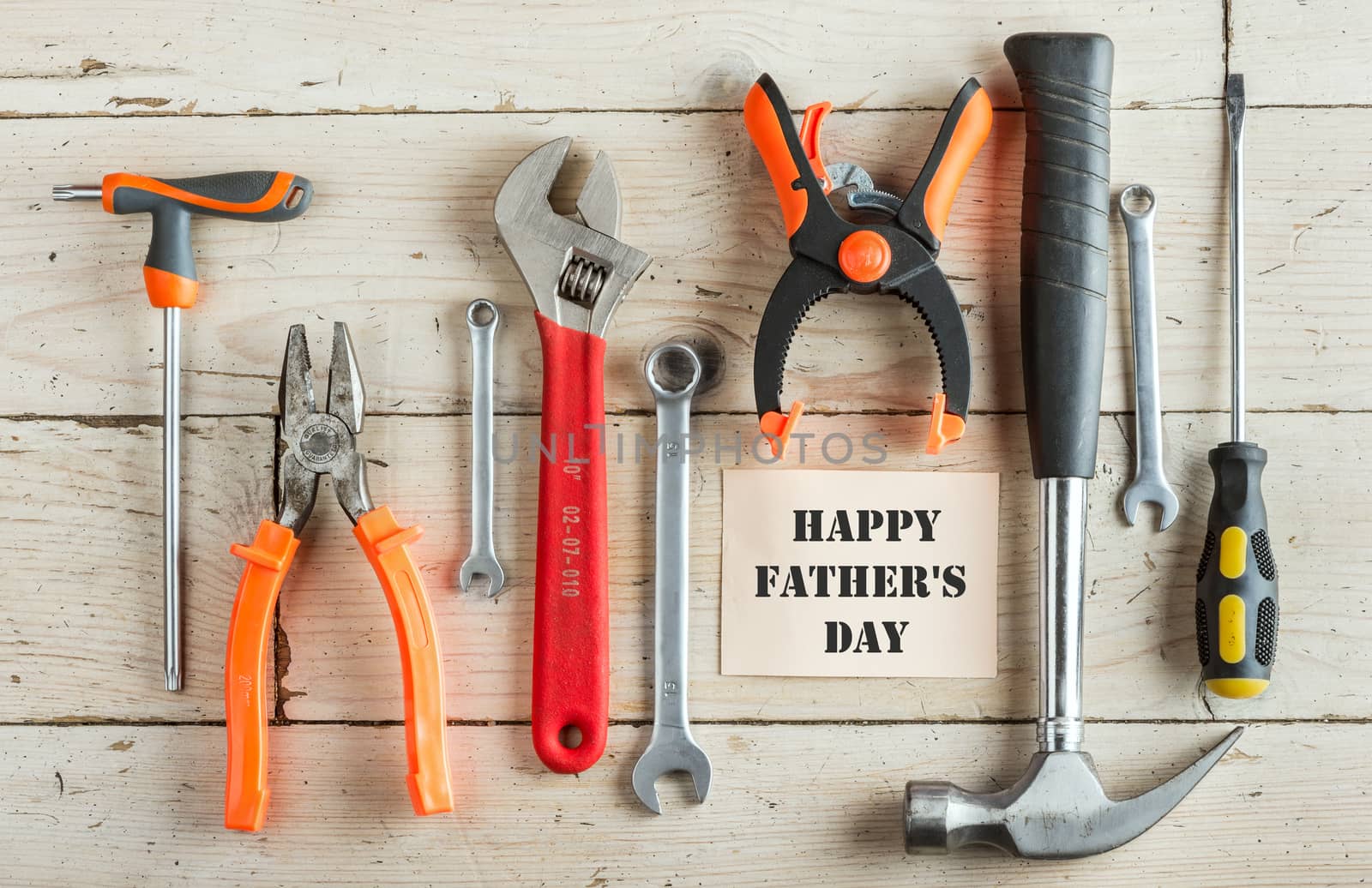 Greeting Card to Happy Father's Day, concept, set of different tools: a hammer, pliers, wrench, screwdriver, various spanners, clamp on a wooden background and tablet for an inscription, 