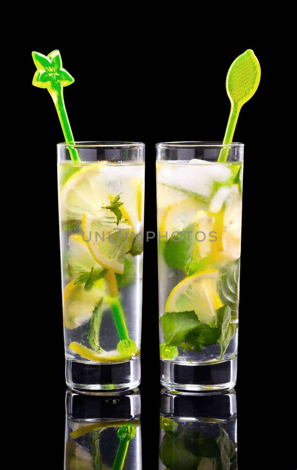 Water with lemon and mint. Cold refreshing, natural, organic, healthy drinks. Two glasses of lemonade with Cocktail Sticks. Isolated on black background