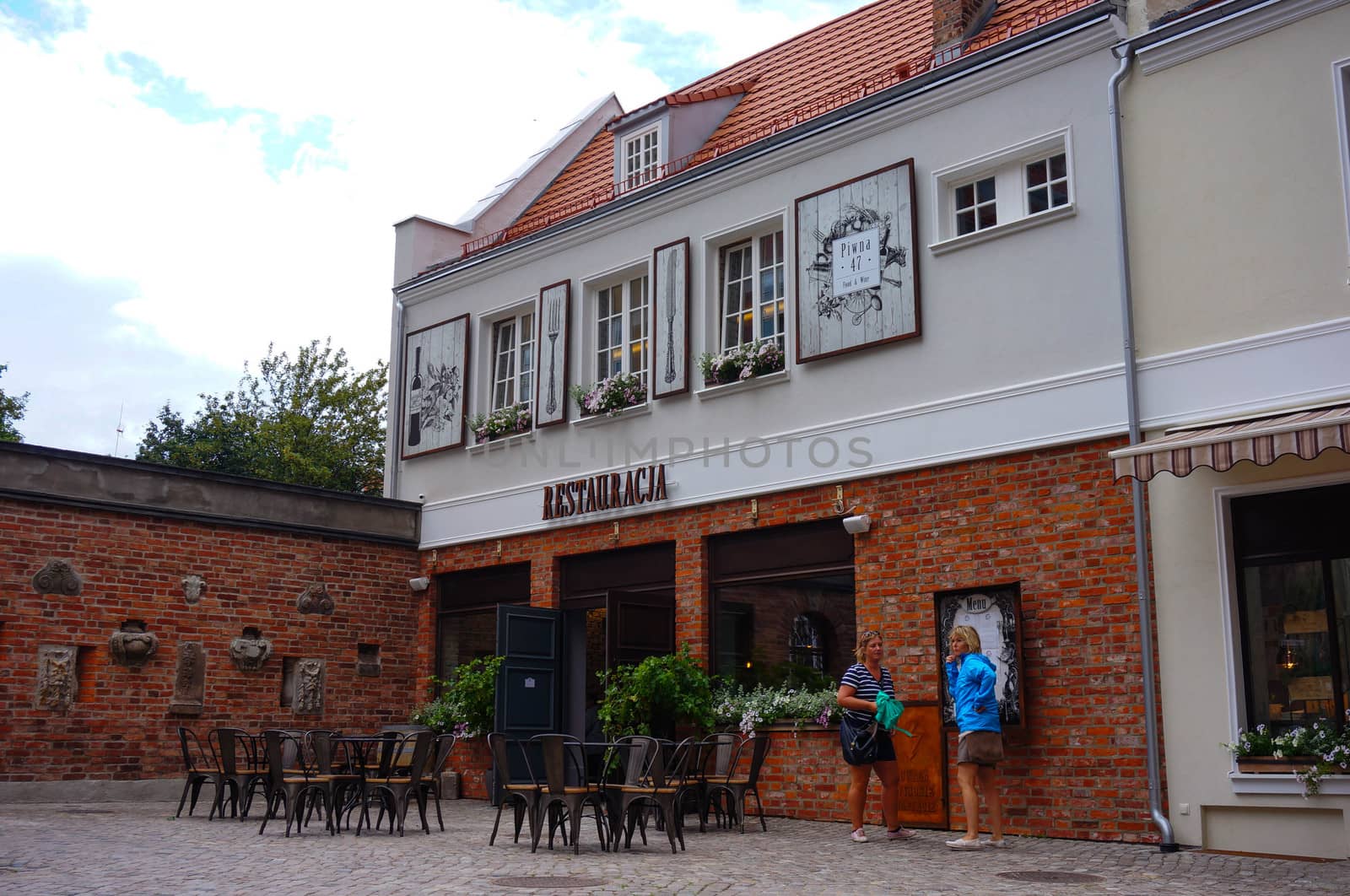 GDANSK, POLAND - JULY 29, 2015: People at a entrance of a restaurant with chairs and tables outdoors