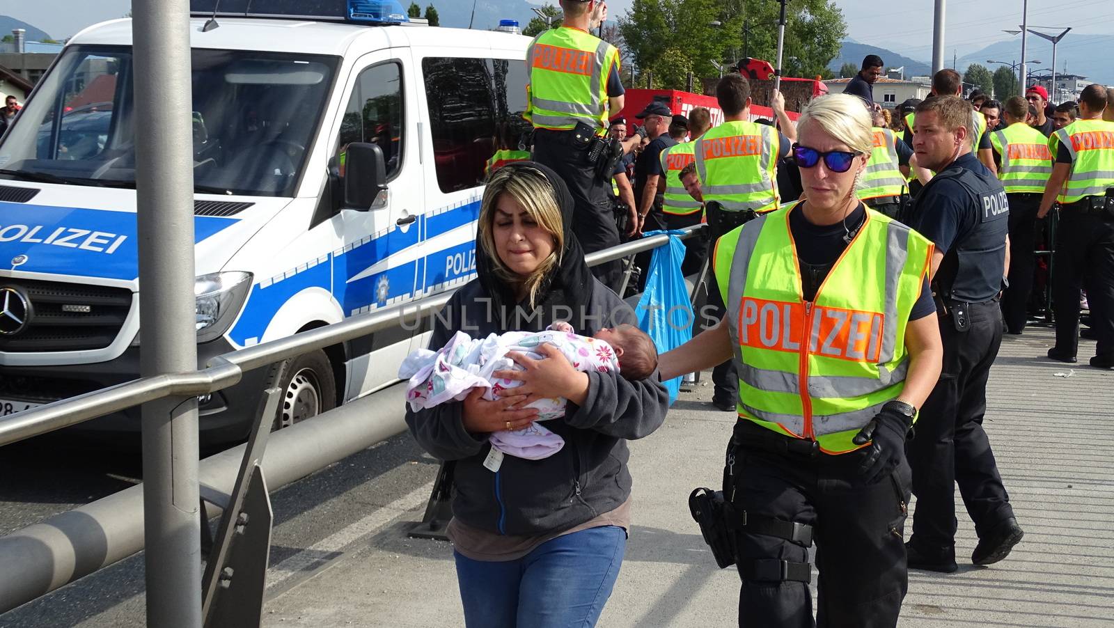 AUSTRIA, Salzburg: A police woman escorts a woman and her baby at the border control in Salzburg, Austria on September 22, 2015 amid an ongoing refugee crisis, which has seen thousands flee from Syria and other war-torn countries for safety in Europe.