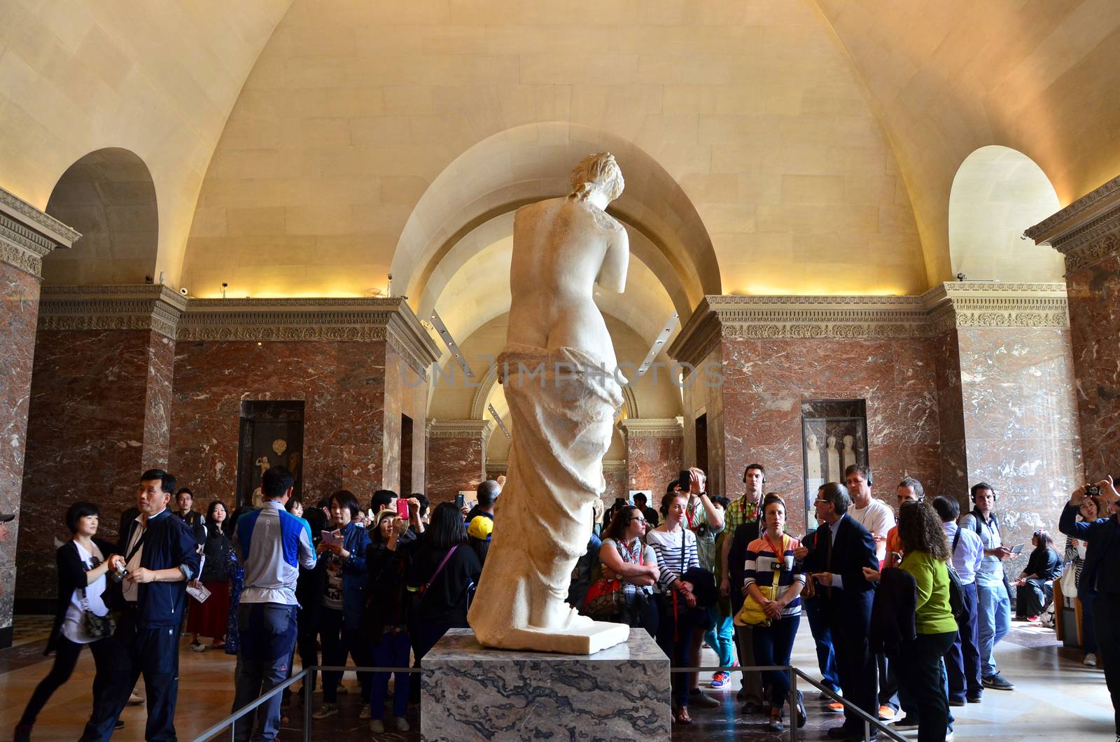 Paris, France - May 13, 2015: Tourists visit The Venus de Milo statue at the Louvre Museum in Paris. by siraanamwong