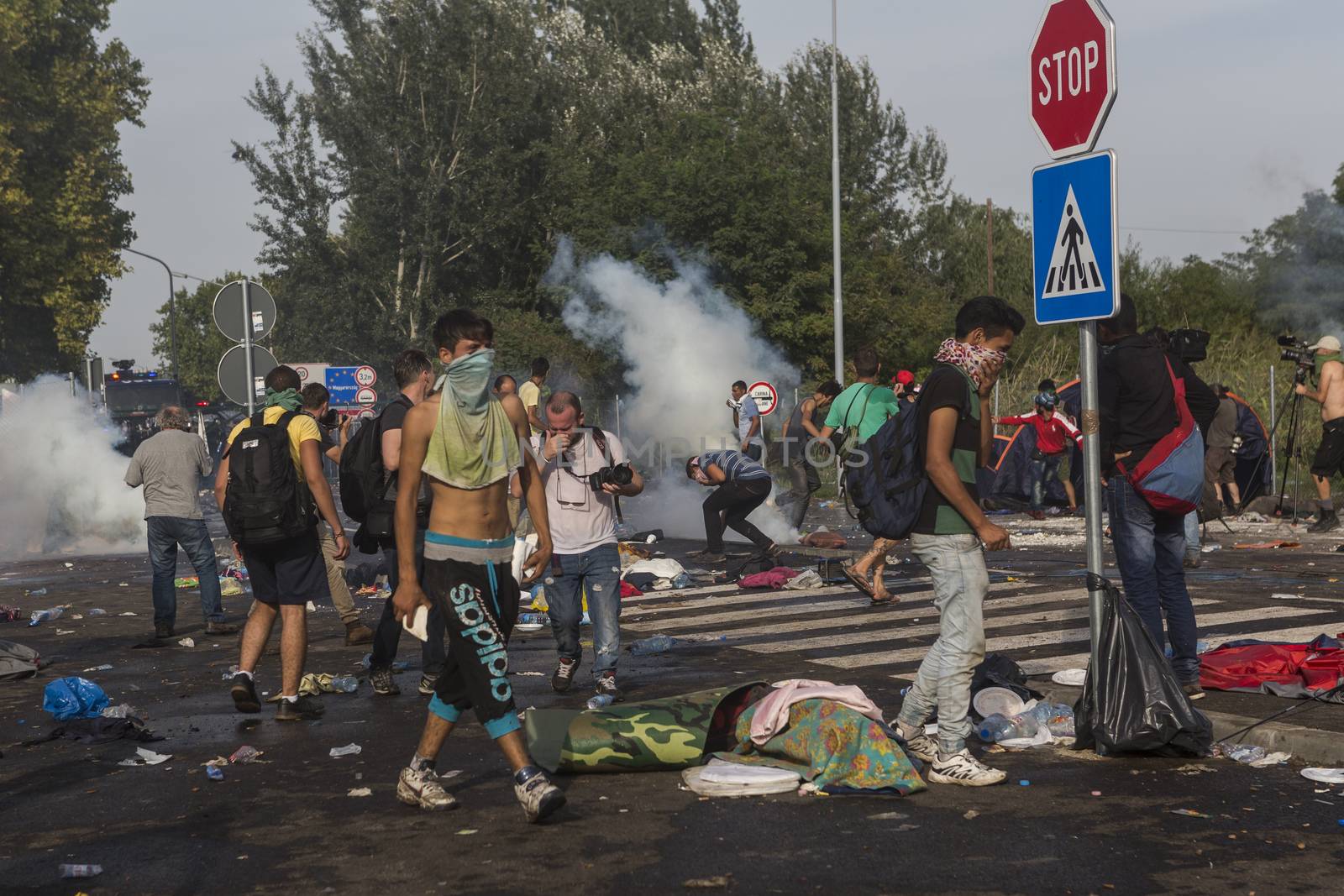 SERBIA, Horgos: People cover their faces as Hungarian police fire tear gas and water cannons into the refugees in the Serbian border town of Horgos on September 16, 2015, after Hungary closed its border in an effort to stem the wave of refugees entering the country. 