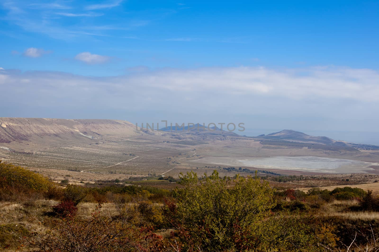 An autumn valley with bushes and blue sky
