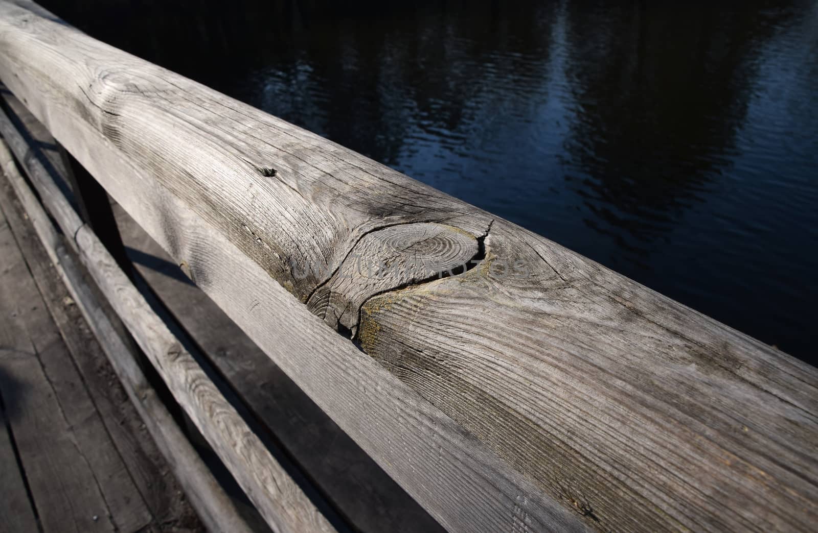 Wooden bridge handrail diagonal shot with blue water background by BreakingTheWalls