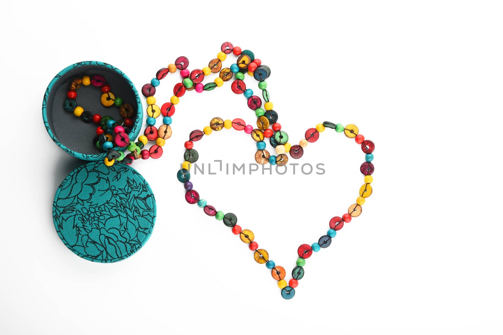 Heart shaped colorful handmade wooden round beads necklace partly taken out of jewelry box isolated on white