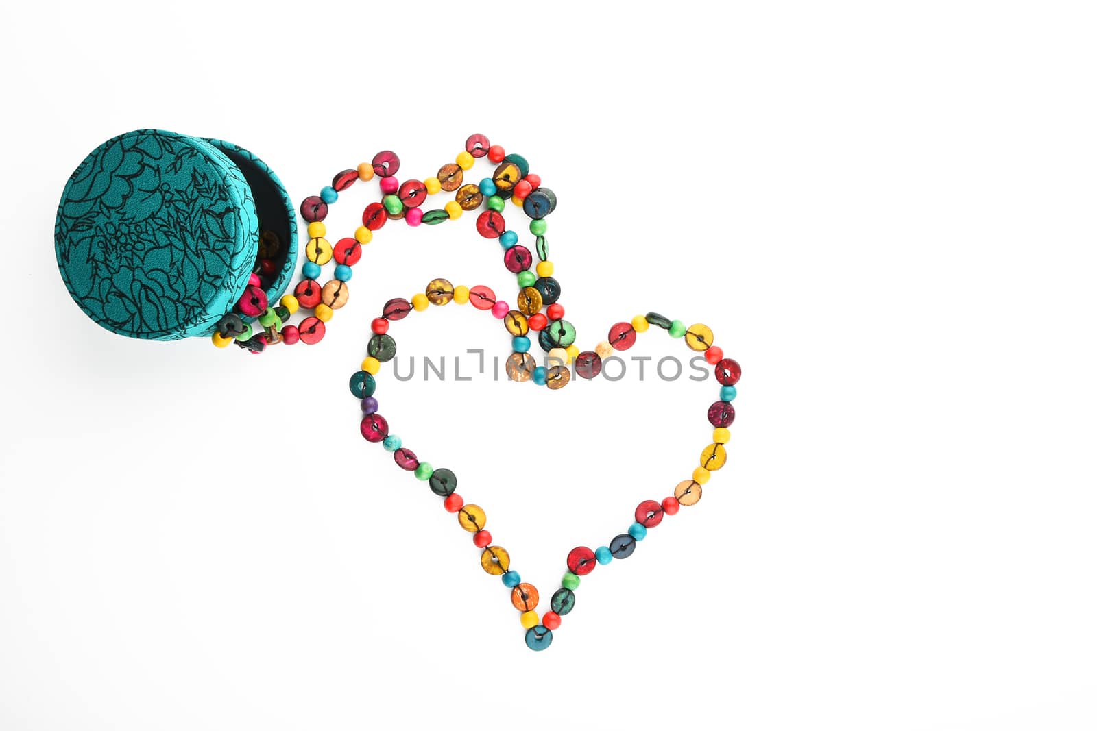 Heart shaped colorful handmade wooden round beads necklace partly taken out of jewelry box isolated on white