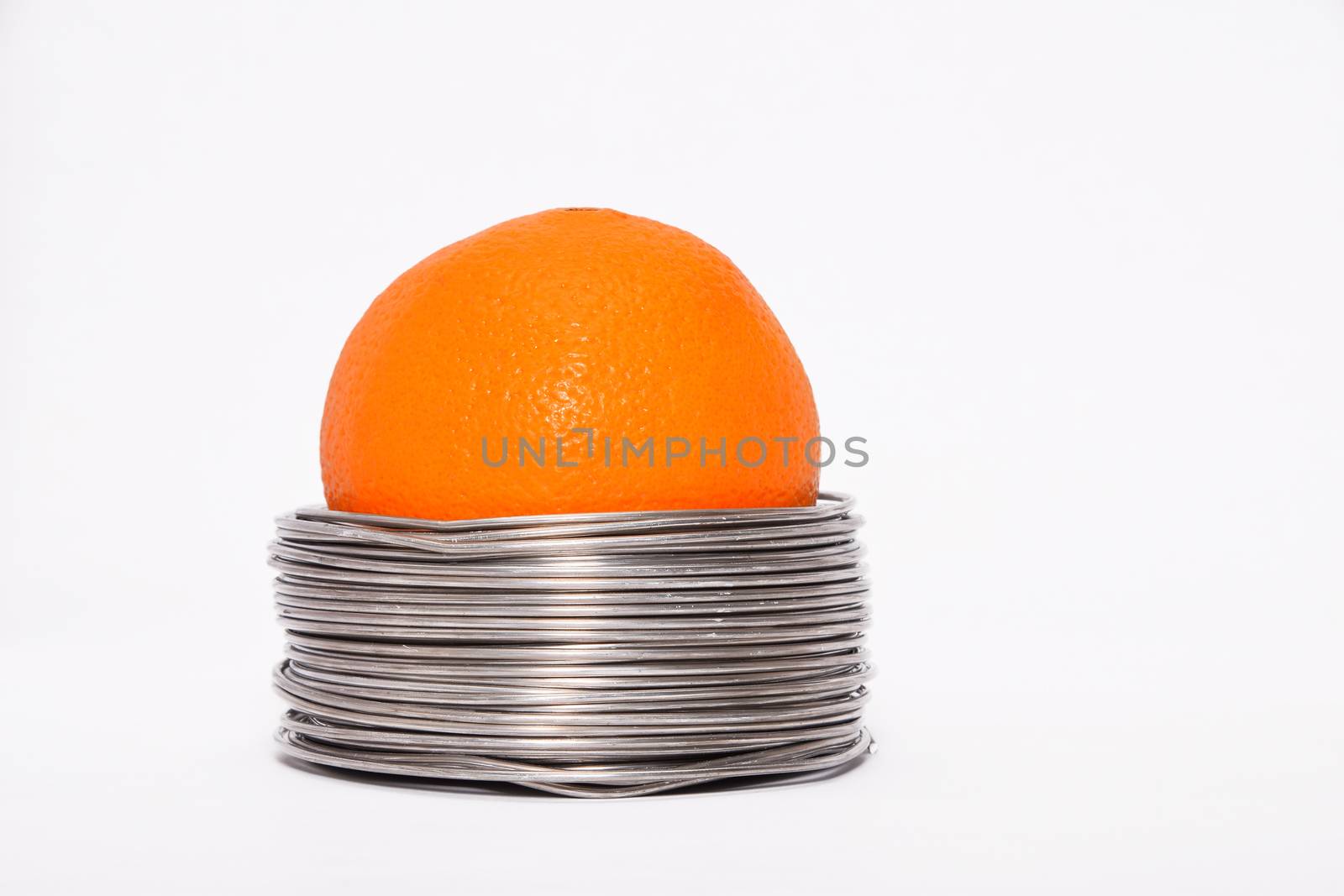 Wired orange: whole orange in coils of aluminium wire isolated o by BreakingTheWalls