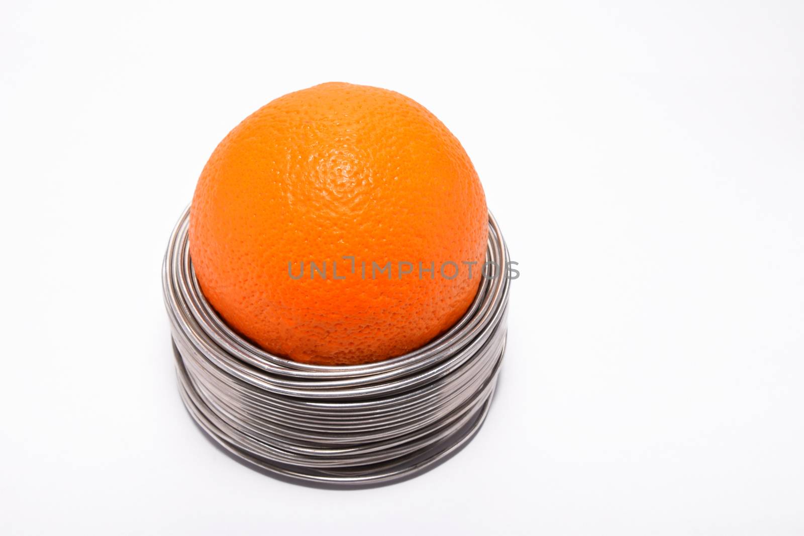 Wired orange: whole orange in coils of aluminium wire isolated o by BreakingTheWalls