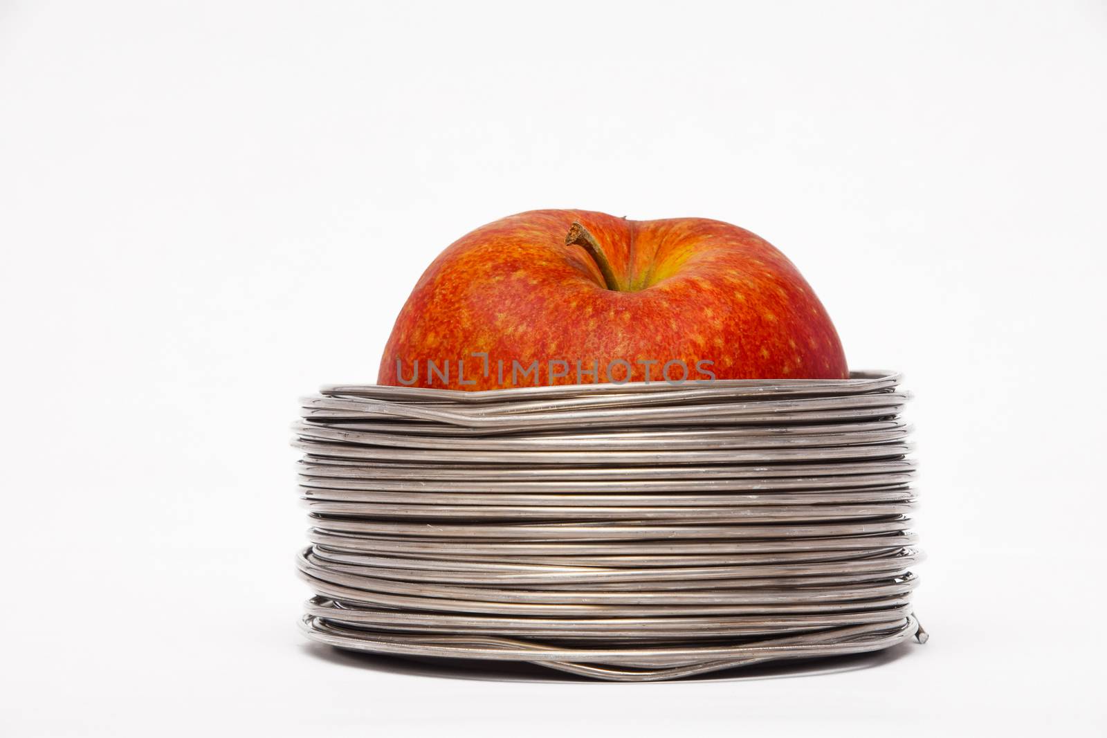 Wired apple: whole red apple in coils of aluminum wire isolated  by BreakingTheWalls