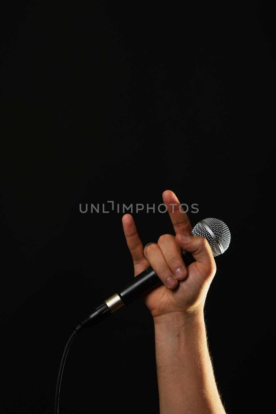 Hand with microphone and devil horns isolated on black by BreakingTheWalls