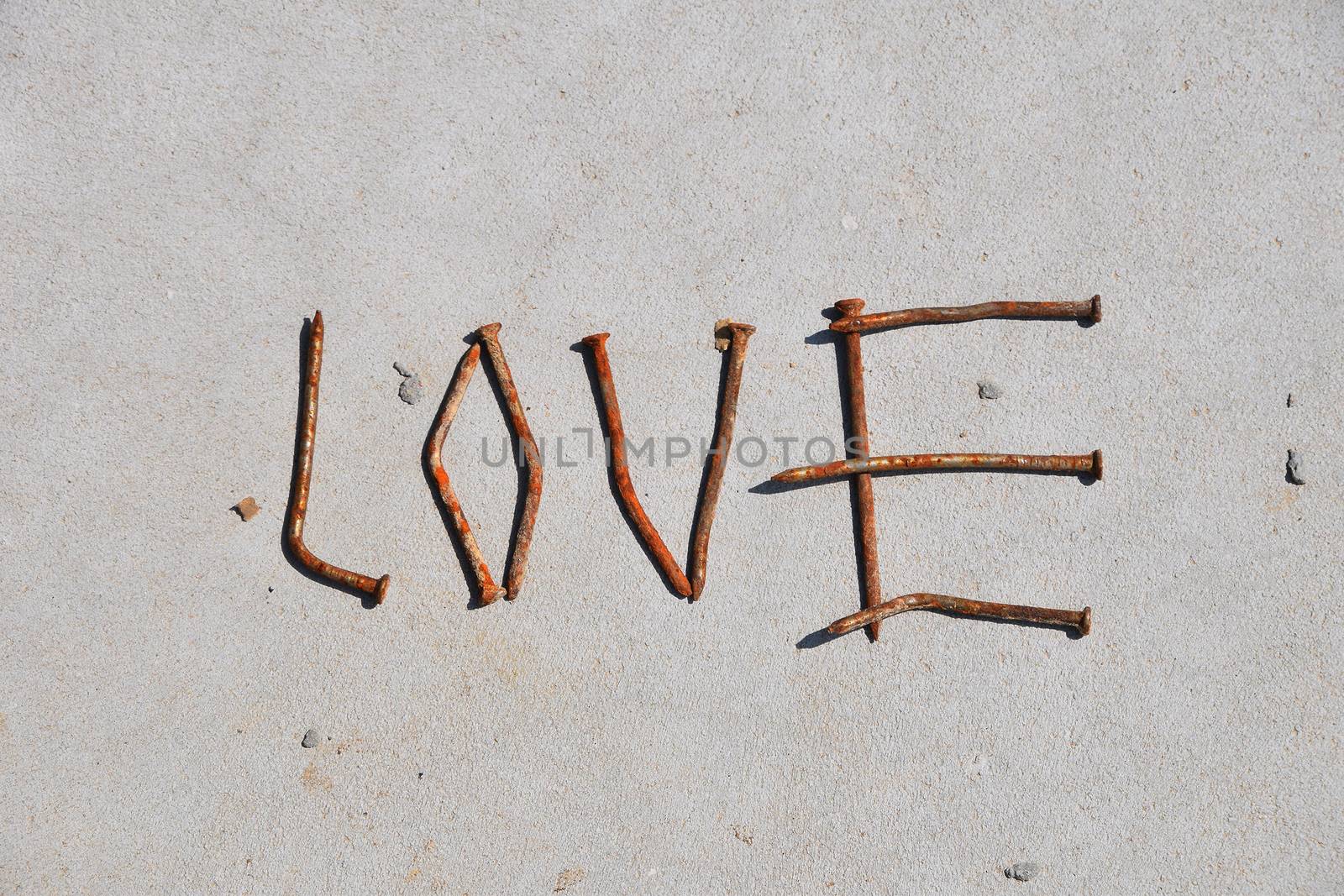 LOVE word formed by rusty nails at grey concrete background by BreakingTheWalls