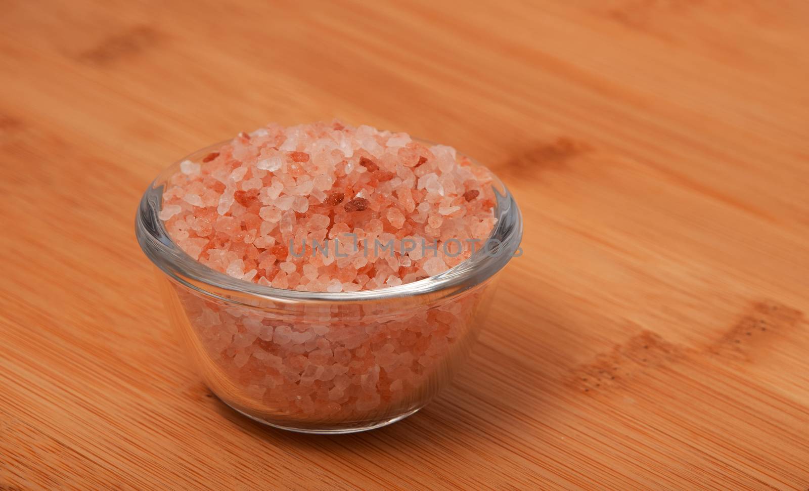 Himalayan pink salt in tiny transparent glass bowl on wooden bam by BreakingTheWalls