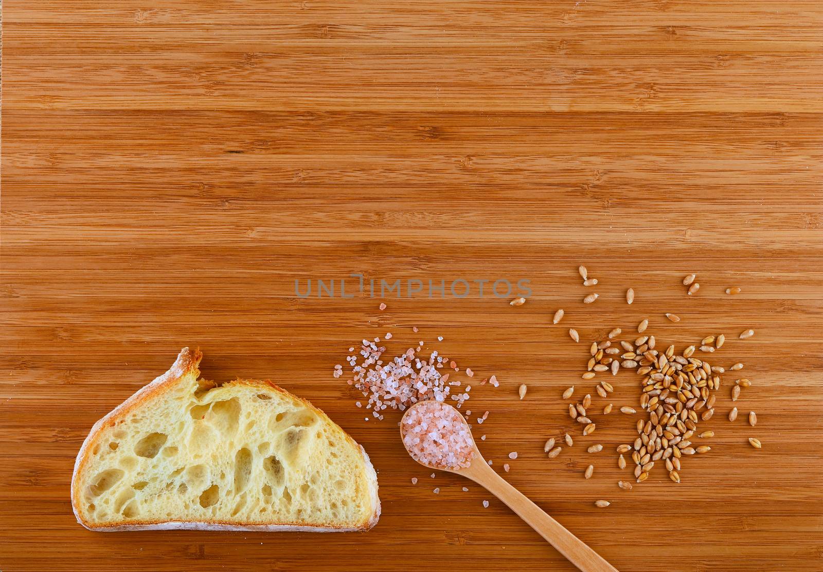 Wooden bamboo cutting board with spoon of pink Himalayan salt, handful of ripe grains and slice of bread - add your text