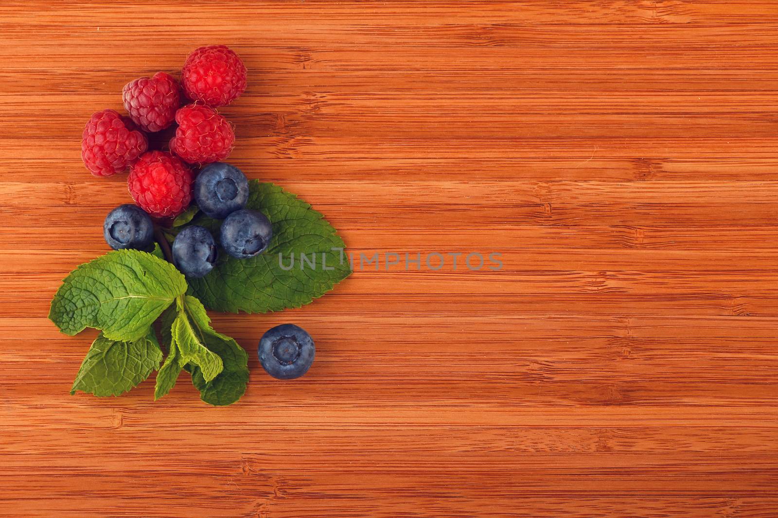 Cutting board with blueberries, raspberries and mint leaves by BreakingTheWalls