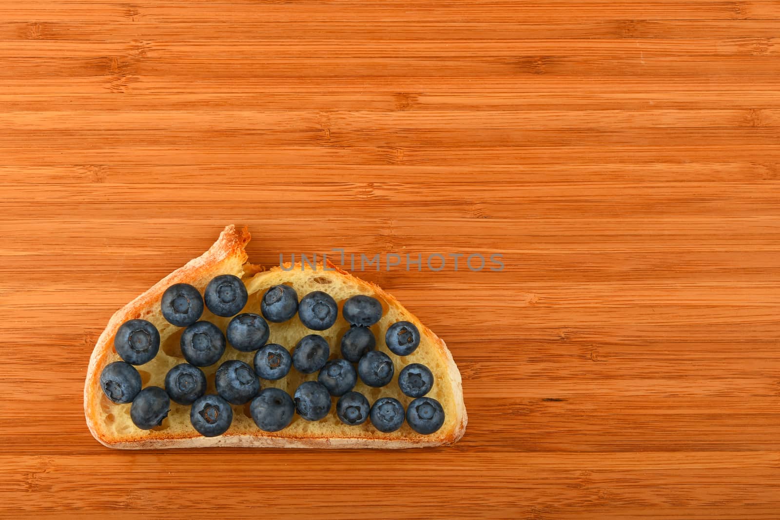 Cutting board with sandwich of blueberries on slice of bread by BreakingTheWalls