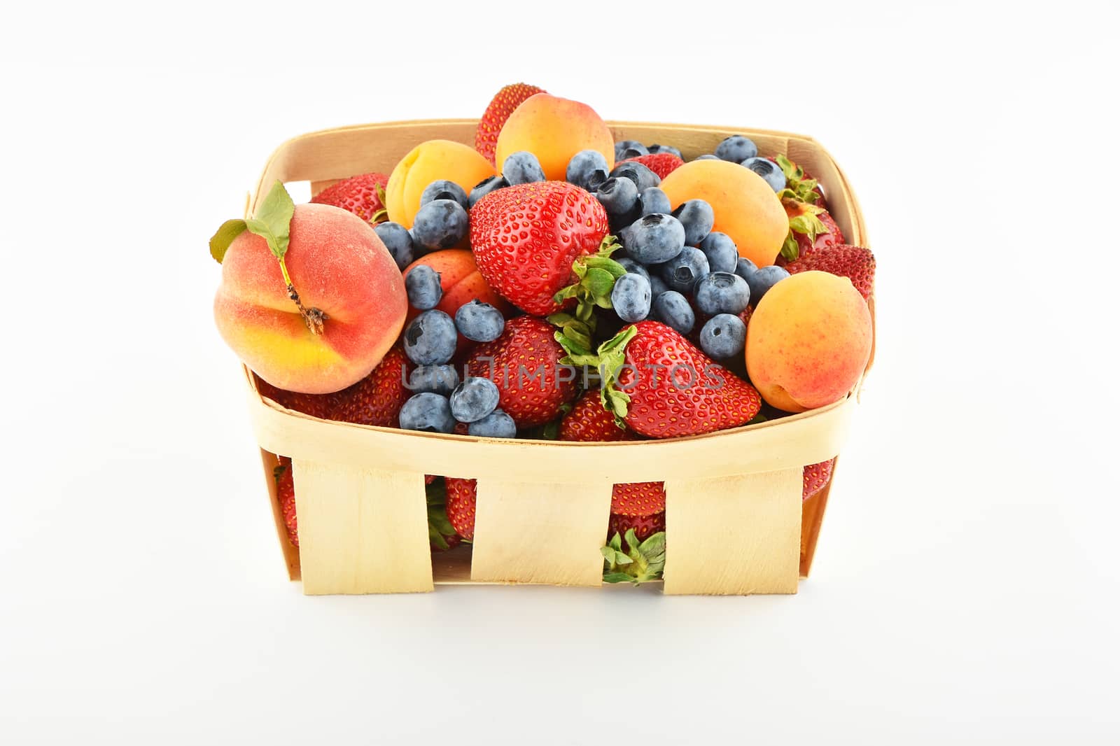 Strawberries, apricots, blueberries, peach in basket isolated on by BreakingTheWalls