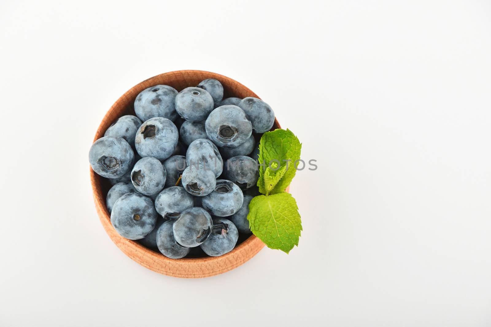 Blueberries and mint leaves in wooden bowl isolated on white by BreakingTheWalls