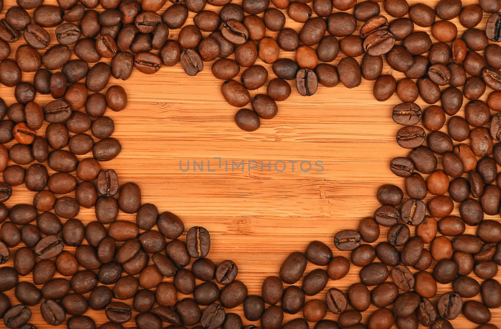 Heart shaped coffee beans frame of Roasted Arabica coffee espresso beans over wooden bamboo board background