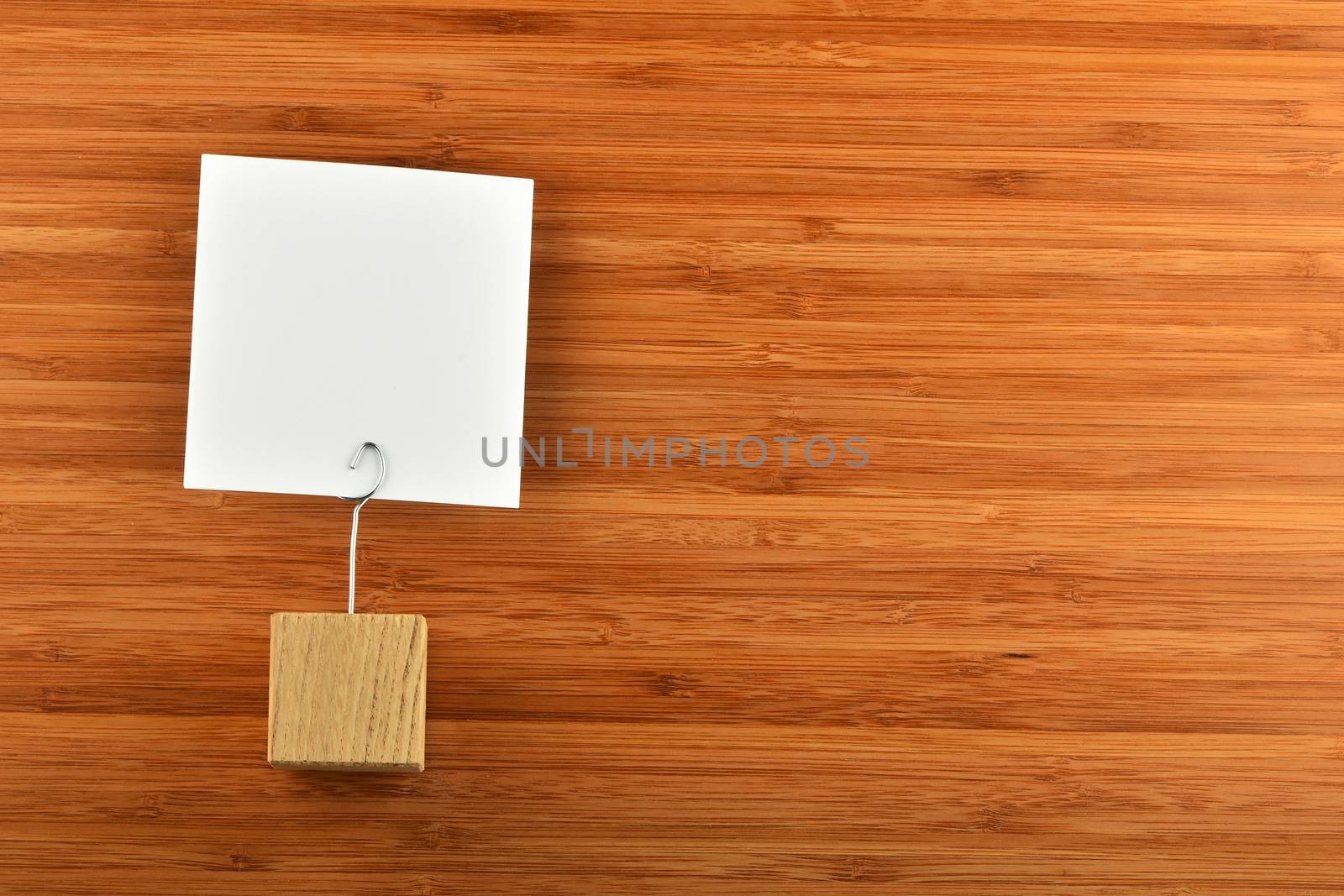 One single white paper note with wooden holder on bamboo wooden background for presentation