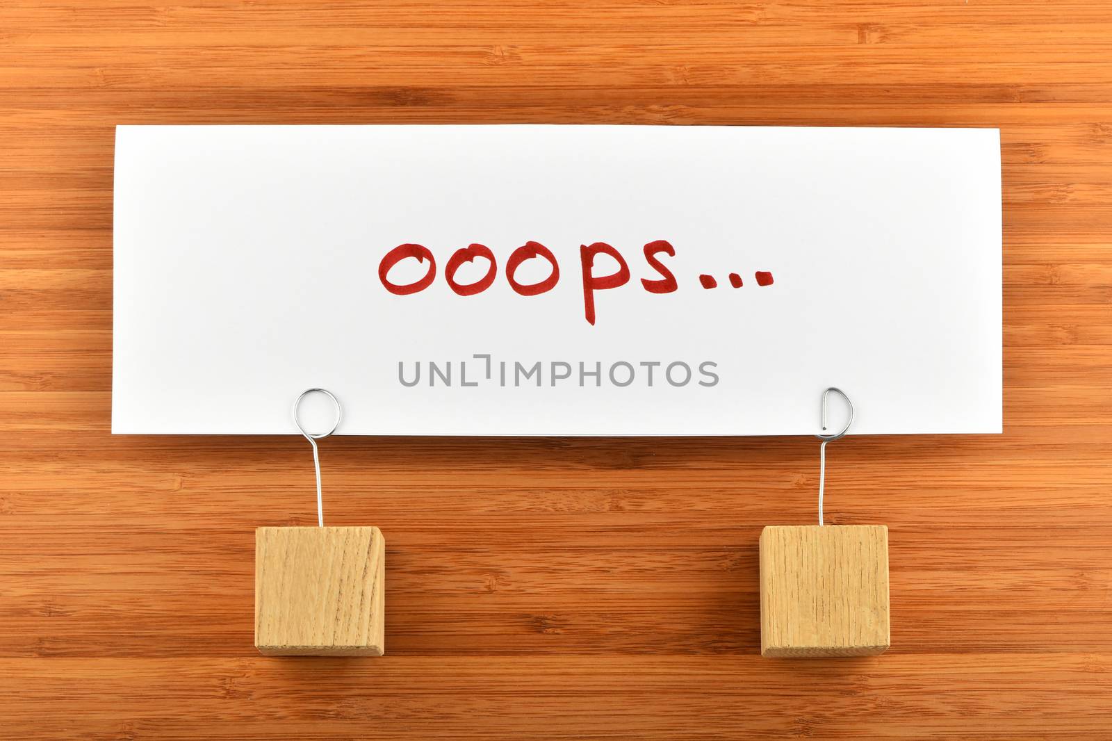 Oops, looks we have problem, one big white paper note with two wooden holders on wooden bamboo background for presentation