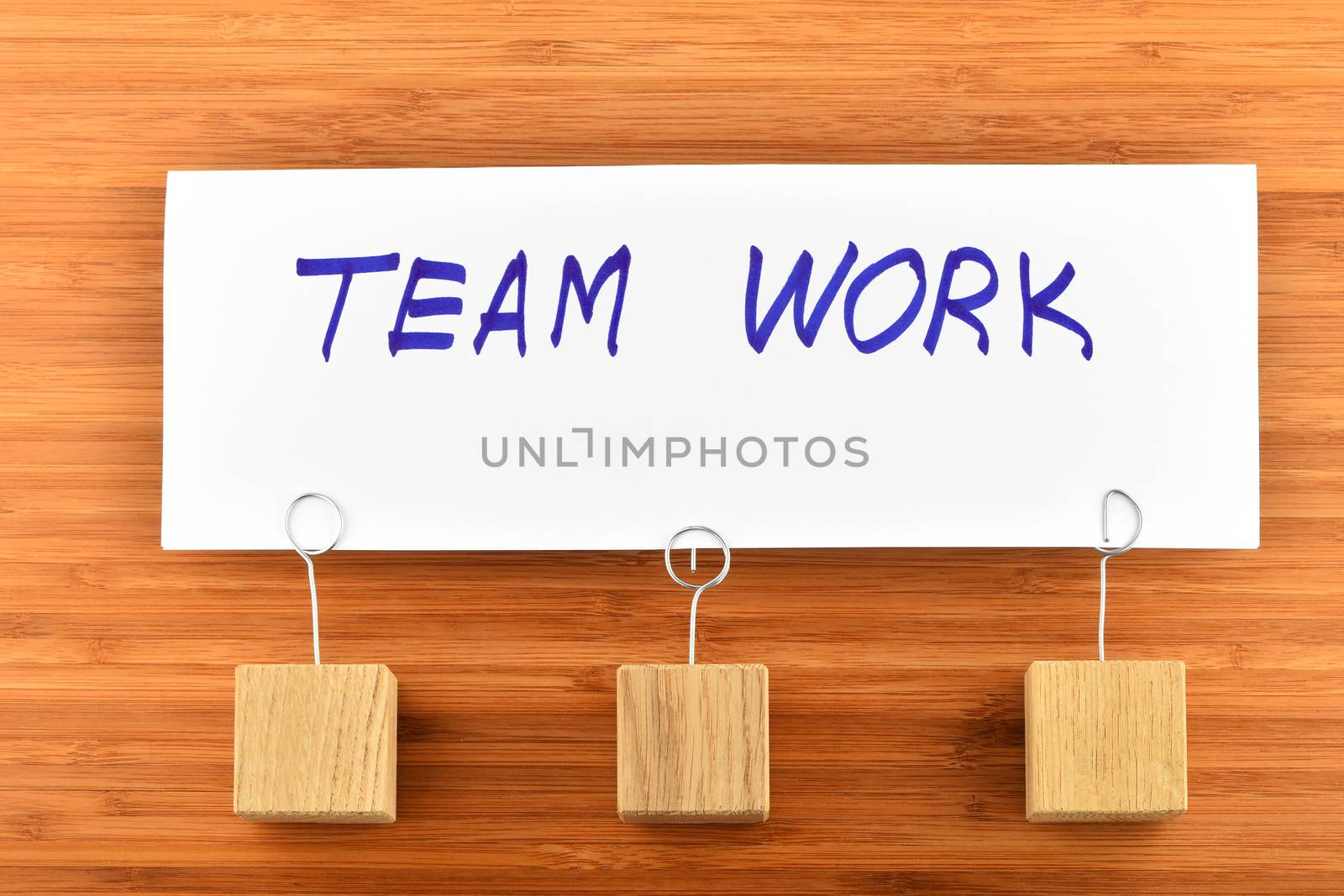 Team work, one paper note with holders on wooden background by BreakingTheWalls