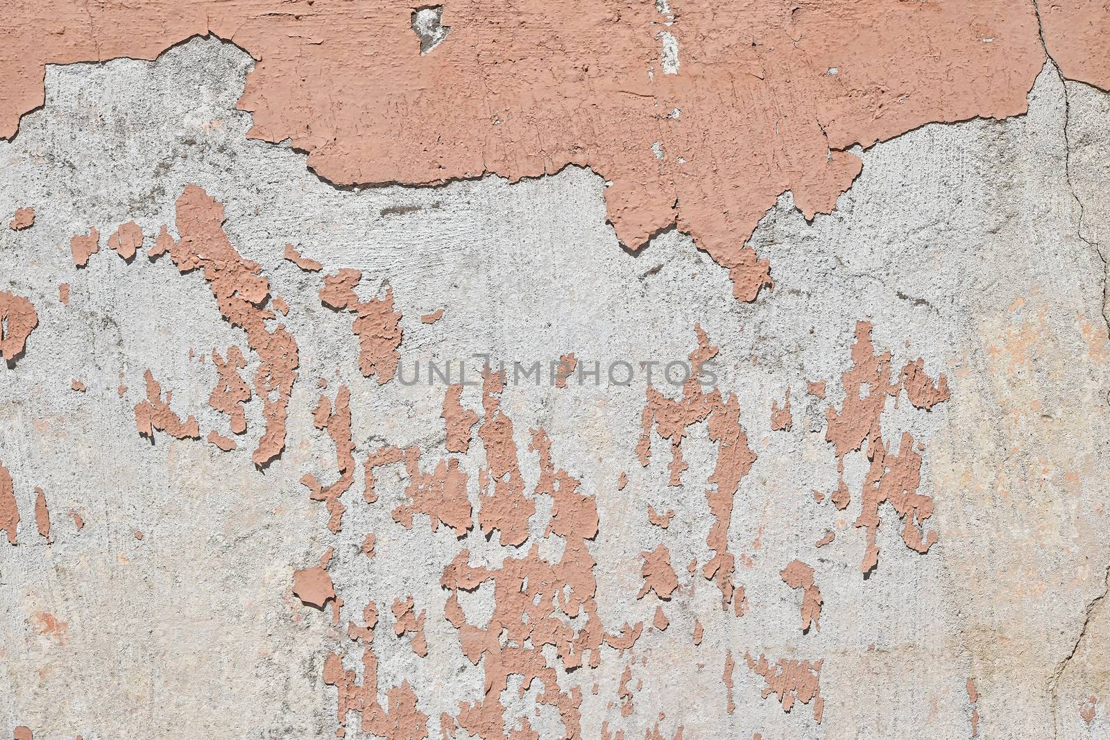 Vintage flakes of old pink paint over grey concrete wall