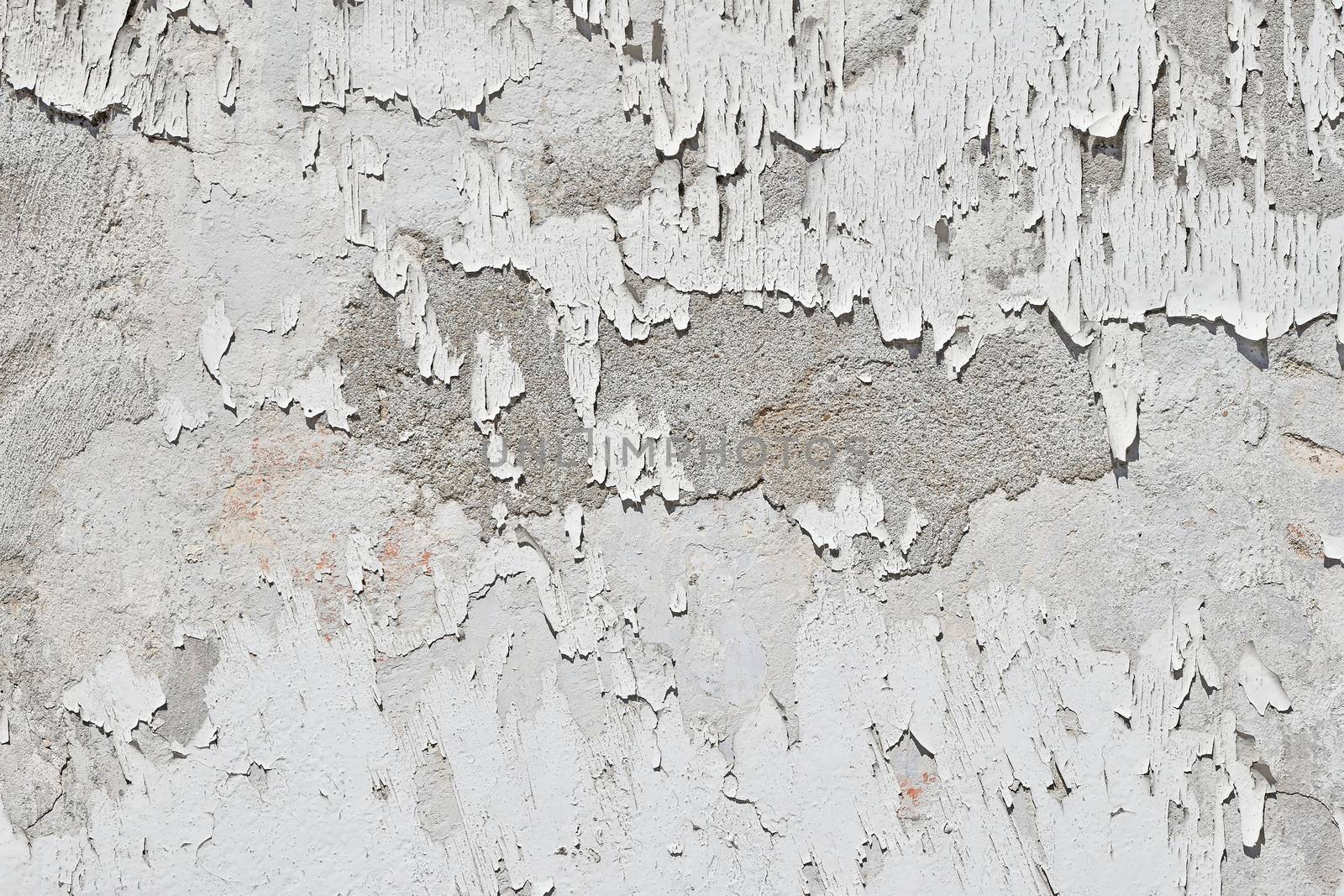 Vintage flakes of old white paint over grey concrete wall