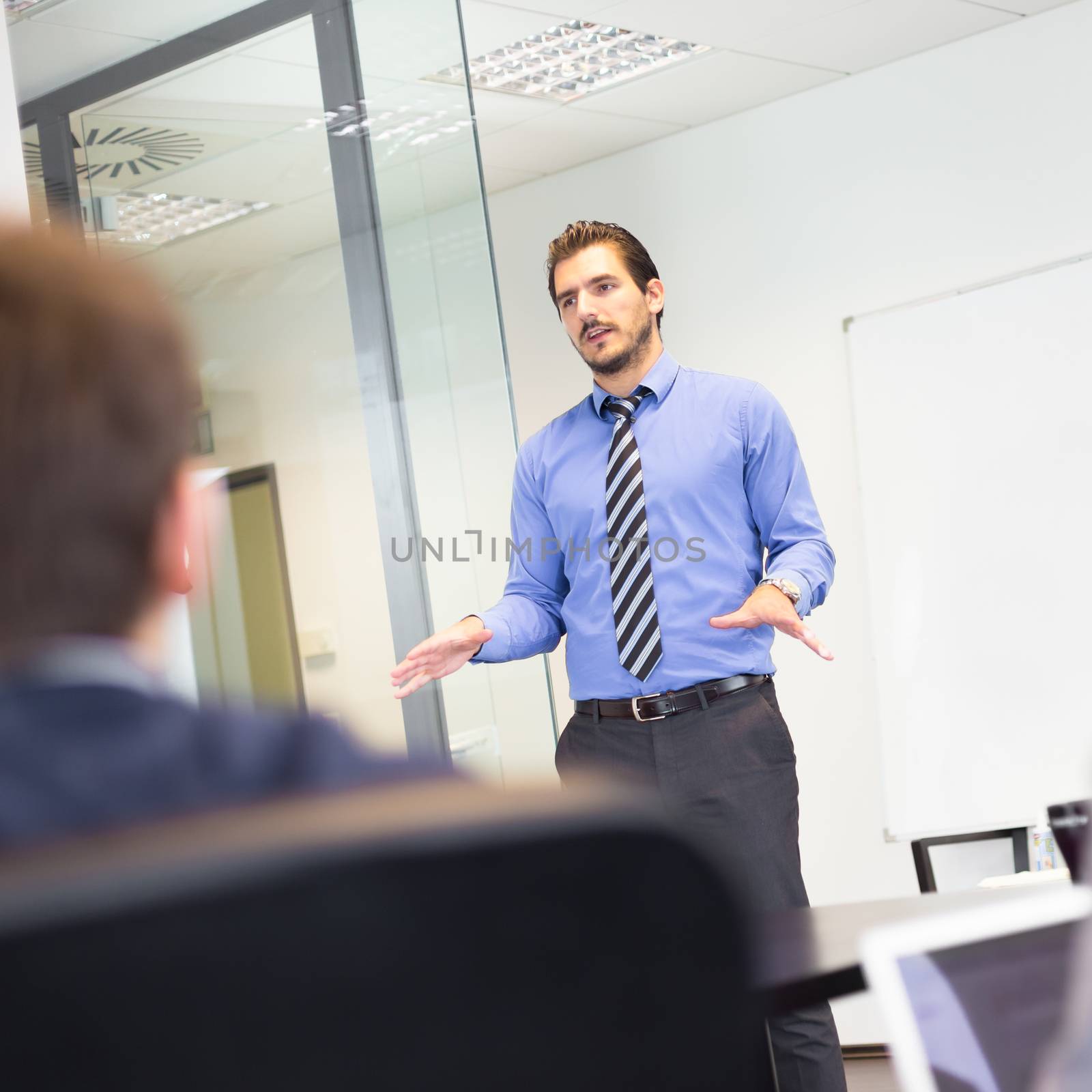 Business man making a presentation at office. Business executive delivering a presentation to his colleagues during meeting or in-house business training, explaining business plans to his employees.